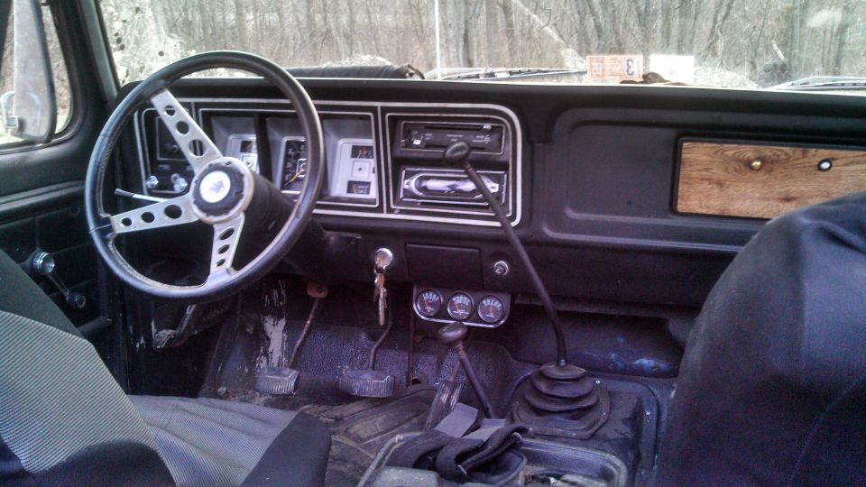 Interior of a 1979 Ford Bronco showing the dashboard, steering wheel, and gear shift