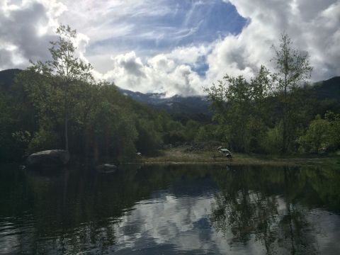 1996 Ford C-350 (Centurion Conversions) - A scenic view of a lake with mountains and trees under a cloudy sky.