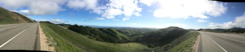 1996 Ford C-350 (Centurion Conversions) - A wide shot captures a highway winding through a lush, green landscape with distant ocean views.