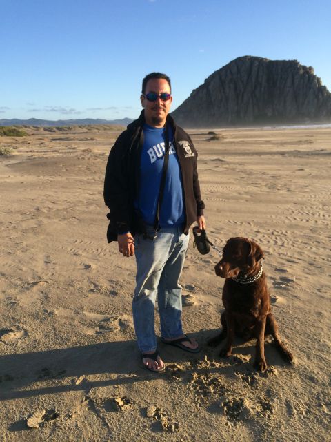 1996 Ford C-350 (Centurion Conversions) - Man and his dog enjoy a day at the beach near a prominent rock formation.