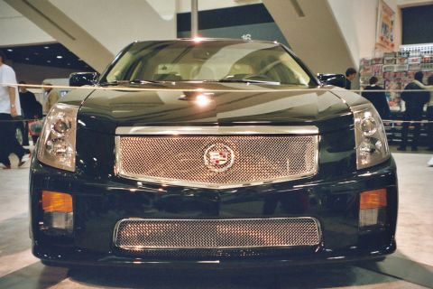 1992 Mercury Grand Marquis - A black Cadillac CTS is displayed indoors, likely at a car show, with its distinctive chrome grille prominently featured.