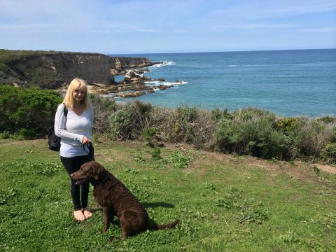 1996 Ford C-350 (Centurion Conversions) - A woman and her dog enjoy a scenic view of the ocean and cliffs on a sunny day.