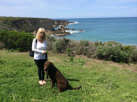 1996 Ford C-350 (Centurion Conversions) - A woman and her dog enjoy a scenic view of the ocean from a cliffside during an April camping trip.