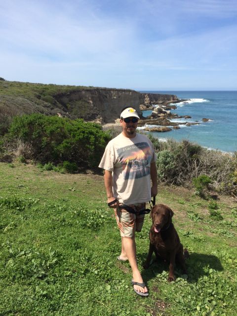 1996 Ford C-350 (Centurion Conversions) - A man and his dog enjoy a scenic view of the coastline on a sunny day.