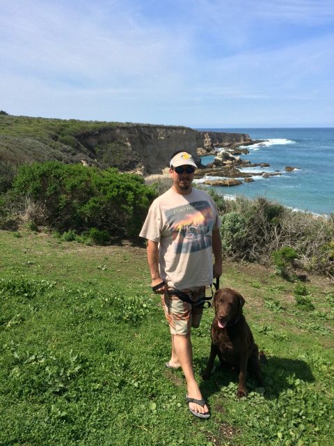 1996 Ford C-350 (Centurion Conversions) - Man and his dog enjoy a scenic view of the ocean and cliffs on a sunny day.