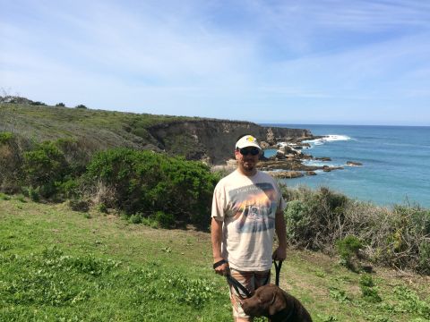 1996 Ford C-350 (Centurion Conversions) - A man and his dog enjoy a scenic view of the coastline on a sunny day.
