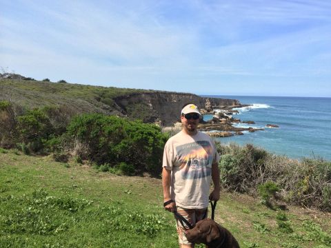 1996 Ford C-350 (Centurion Conversions) - A man and his dog enjoy a scenic view of the coastline on a sunny day.