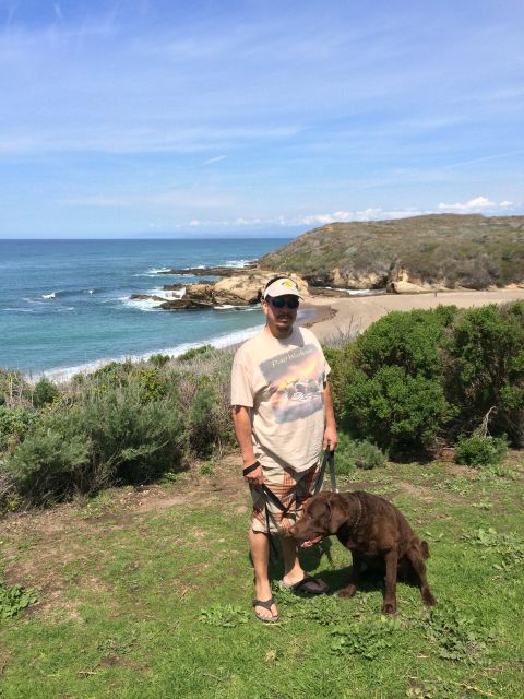 1996 Ford C-350 (Centurion Conversions) - A man and his dog enjoy a scenic view of the ocean from a cliffside overlook.