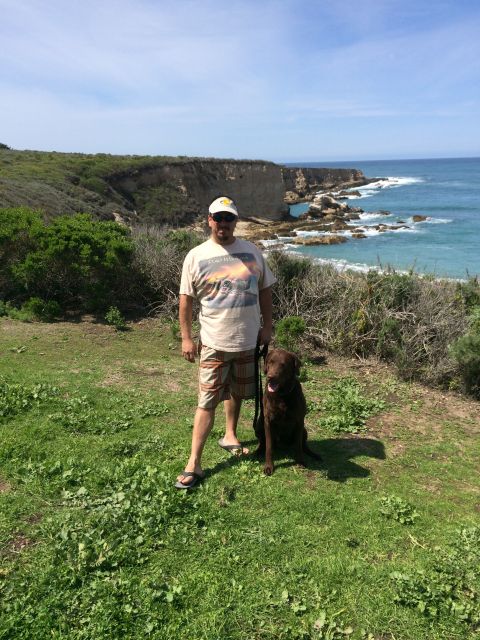 1996 Ford C-350 (Centurion Conversions) - A man and his dog enjoy a scenic view of the ocean and cliffs during an April camping trip.