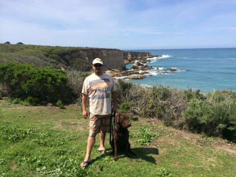 1996 Ford C-350 (Centurion Conversions) - A man and his dog enjoy a scenic view of the coastline on a sunny day.