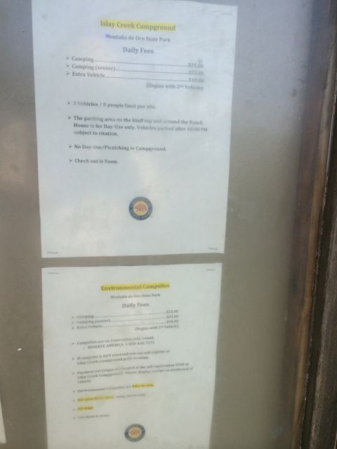 1996 Ford C-350 (Centurion Conversions) - A sign displays daily fees and rules for Islay Creek Campground and Environmental Campsites at Montaña de Oro State Park.