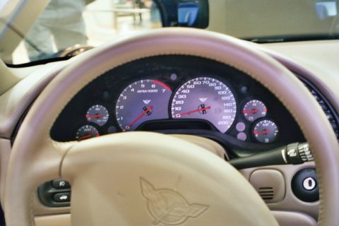 1992 Mercury Grand Marquis - The interior of a Corvette shows its dashboard, steering wheel, and gauges, with the Corvette emblem visible on the wheel.