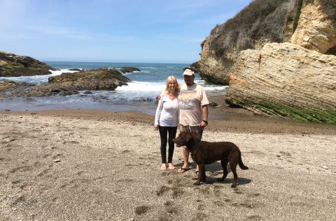 1996 Ford C-350 (Centurion Conversions) - A couple and their dog enjoy a day at the beach near rocky coastal formations.