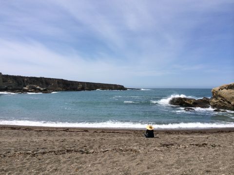 1996 Ford C-350 (Centurion Conversions) - A solitary figure enjoys a day of fishing by the sea, with cliffs in the background under a partly cloudy sky.