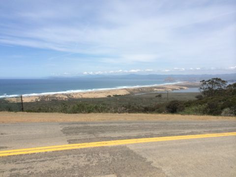1996 Ford C-350 (Centurion Conversions) - A scenic view of the coast, the ocean, a sandy beach, and a road with double yellow lines.