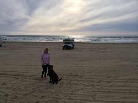 1996 Ford C-350 (Centurion Conversions) - A woman and her dog stand on a beach with a truck camper in the background.