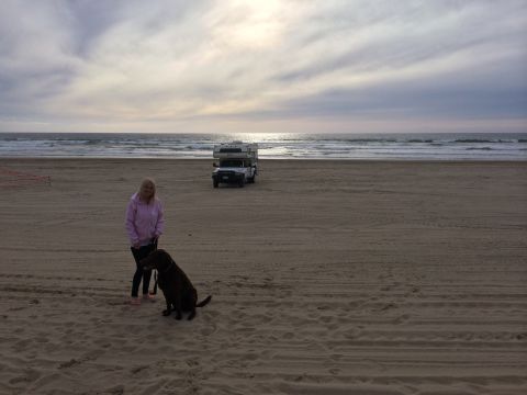 1996 Ford C-350 (Centurion Conversions) - A woman and her dog enjoy a day at the beach with a truck camper in the background.