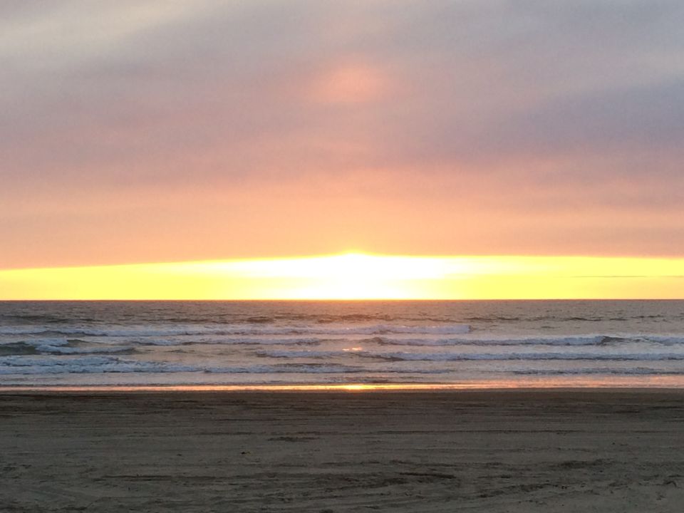 Beach scene with waves and a colorful sunset sky