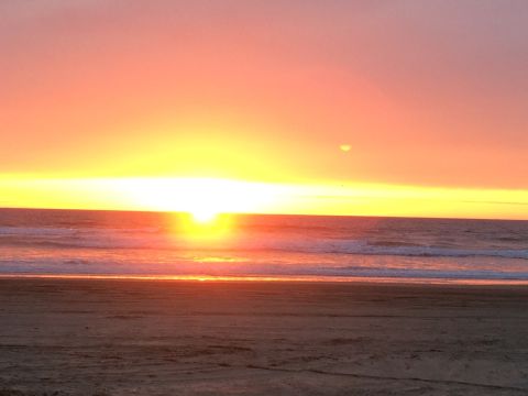 1996 Ford C-350 (Centurion Conversions) - Sunset over the ocean with waves crashing on a sandy beach.