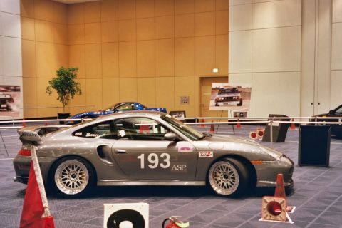 1992 Mercury Grand Marquis - A silver Porsche 911 Turbo is displayed indoors with other vehicles visible in the background.