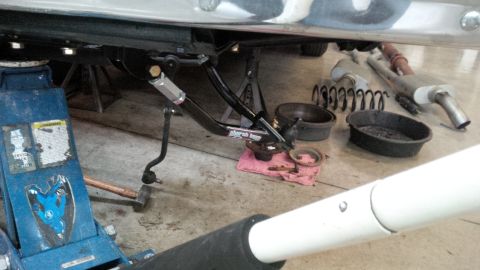 1963 Chevrolet Nova - Car suspension parts are laid out on the garage floor, with a jack and other tools nearby.