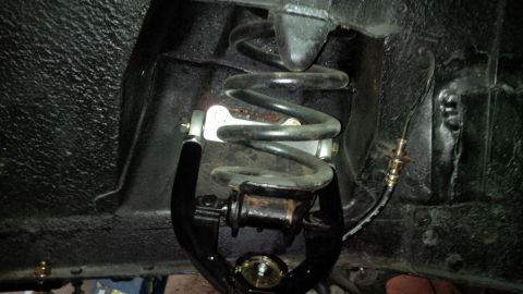 1963 Chevrolet Nova - Underside view of a vehicle's suspension system, focusing on a coil spring and control arm.