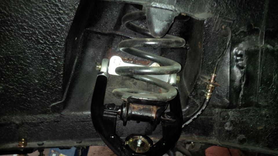 Close-up of a black suspension component with a coil spring and brake line