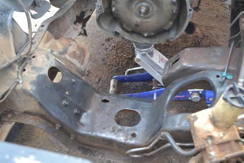 1981 Ford F-250 - The underside of a vehicle shows its frame and transmission being worked on with multiple jacks.
