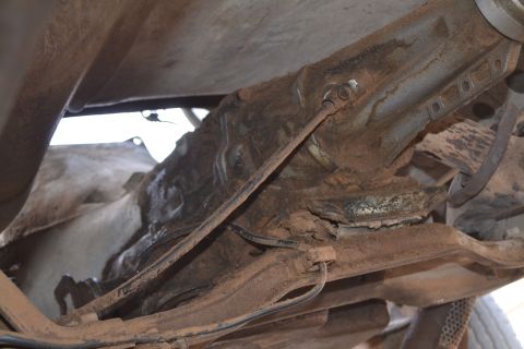 1981 Ford F-250 - The undercarriage of a vehicle shows significant rust and wear on its suspension and brake lines.