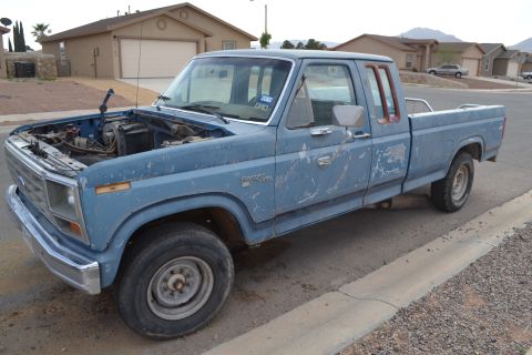 1981 Ford F-250 - This blue pickup truck, likely an early 1980s Ford F-Series, is parked on a residential street with its hood open.