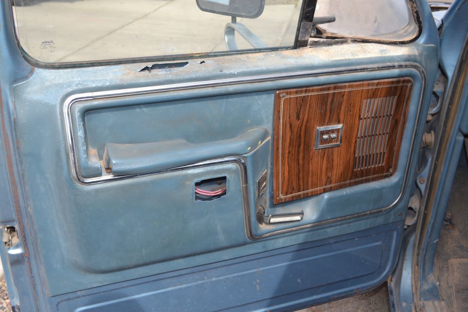 Blue truck door panel with wood grain trim and a broken door handle