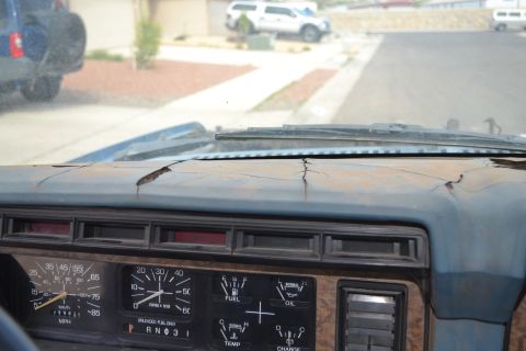 1981 Ford F-250 - Interior view of a vehicle's dashboard, showing cracked plastic and a view of the street with other cars.