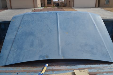 1981 Ford F-250 - A blue truck hood is shown from above, resting in the bed of a pickup truck.
