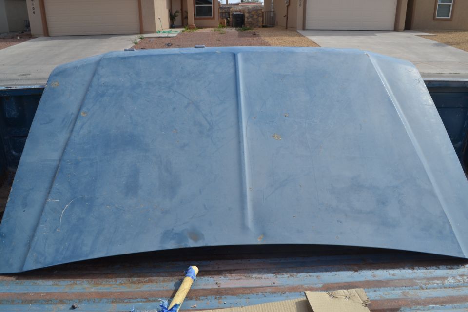 Blue truck hood resting in truck bed