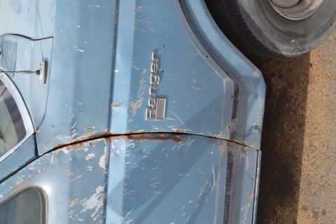 1981 Ford F-250 - Close-up of a weathered blue truck fender, showing rust and the "Ranger" emblem.