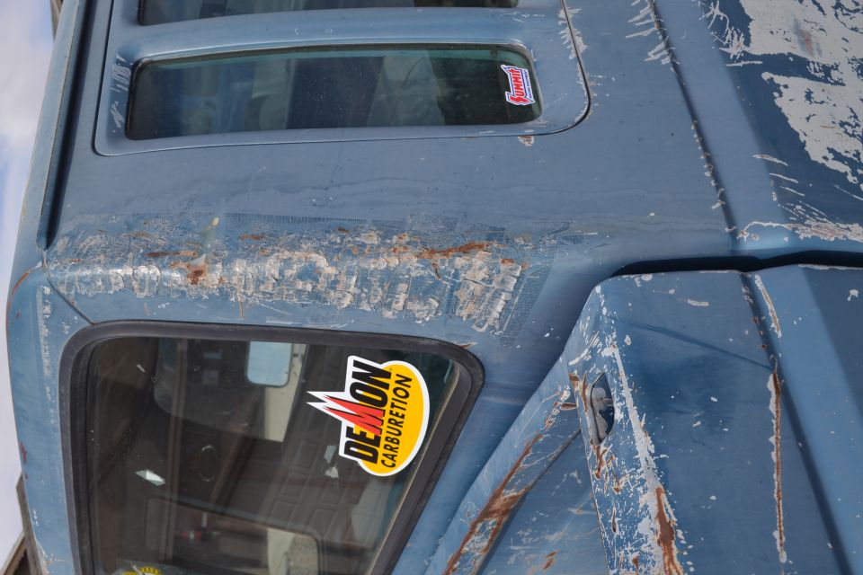 1981 Ford F-250 roof with peeling paint and rust, showing a Demon Carburetion sticker on the side window