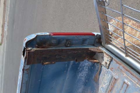 1981 Ford F-250 - Rusted corner of a blue truck bed, showing the taillight assembly and metal reinforcement.