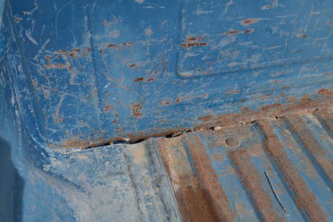 1981 Ford F-250 - The interior of a blue truck bed shows significant rust and wear, indicating age and exposure.