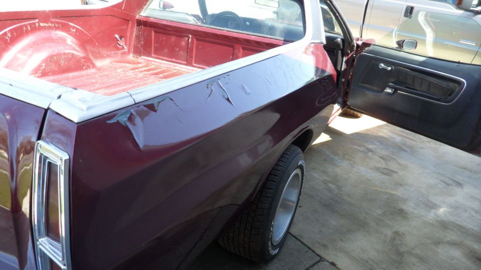 1972 Ford Ranchero with open driver's door, showing pickup bed and rear wheel. Another vehicle is parked nearby