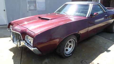 1972 Ford Ranchero - A maroon 1972 Ford Ranchero is parked in front of a building with a window reflecting another vehicle.
