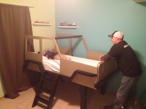 2005 Jeep Wrangler - A child sleeps in a bed designed to resemble a Jeep, with a man standing nearby.