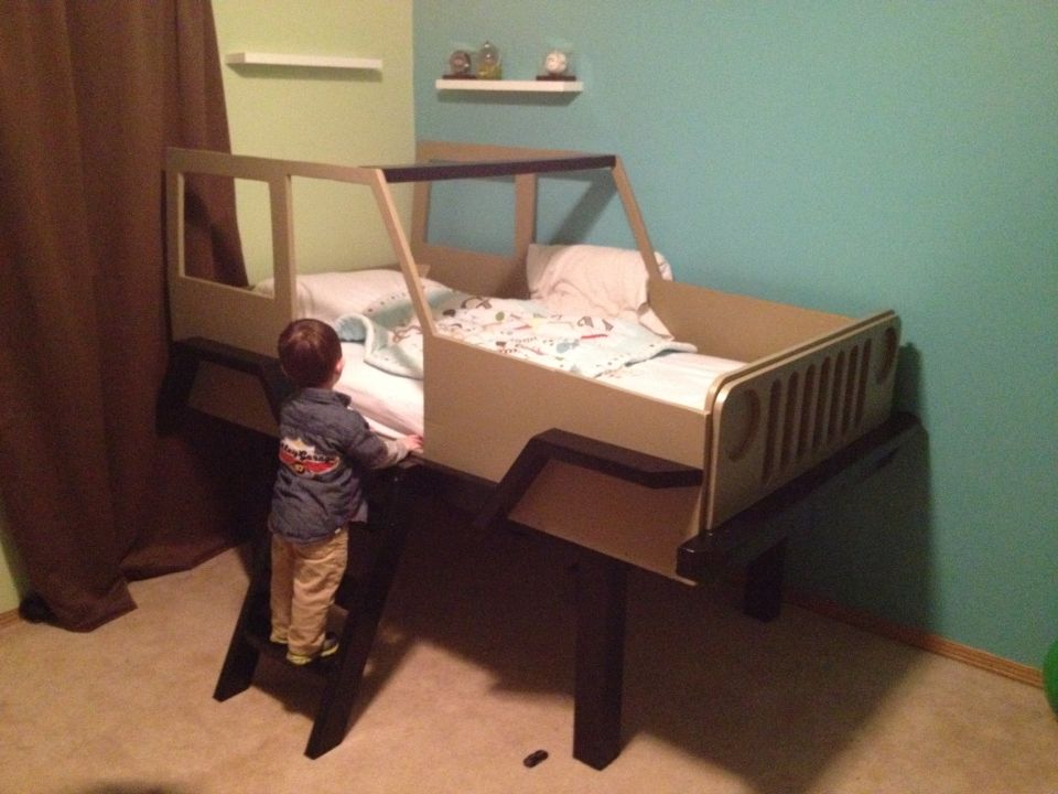 Child's bed designed as a Jeep Wrangler, with a child on a ladder
