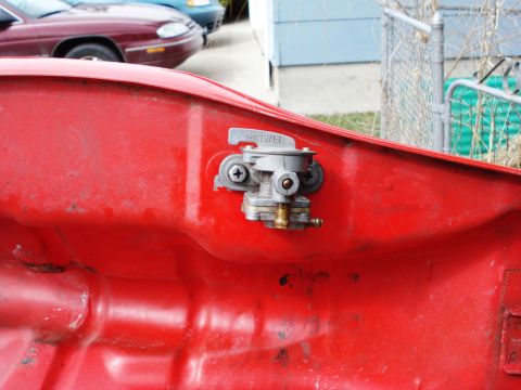 2008 Ford Crown Victoria - Close-up of a fuel petcock attached to a red gas tank, with the word "FUEL" visible on the lever.