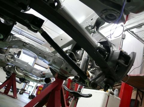 Underside of a car on jack stands, showing suspension and frame components