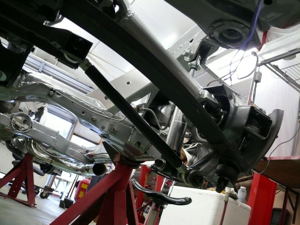 Underside of a car on jack stands, showing suspension and frame components
