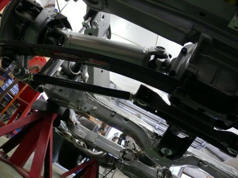 Undercarriage of a vehicle on red jack stands, showing suspension and drivetrain components