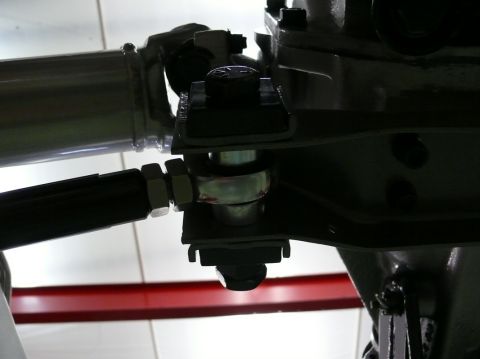 Close-up of a metal linkage with bolts and nuts, part of a vehicle's suspension system