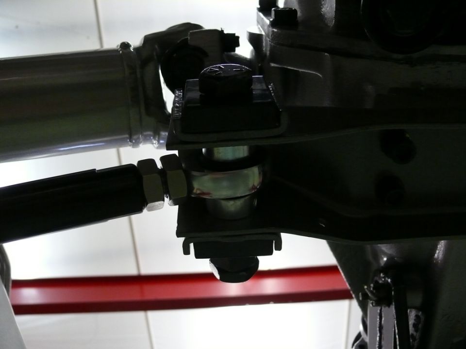Close-up of a metal linkage with bolts and nuts, part of a vehicle's suspension system