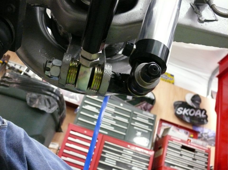 Close-up of rear suspension linkage and shock absorber with toolbox in background