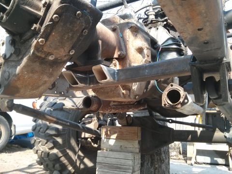 1986 Ford Bronco - Undercarriage view of a vehicle's drivetrain and suspension system, showing various metal components.